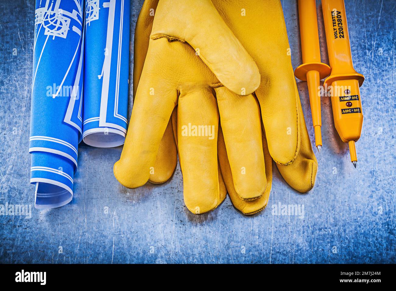 Gants de protection jaune pour testeur électrique plans de construction laminés bleus sur fond métallique. Banque D'Images