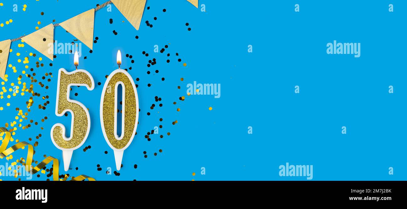 Bougie de célébration en or numéro 50 sur fond bleu. Banque D'Images