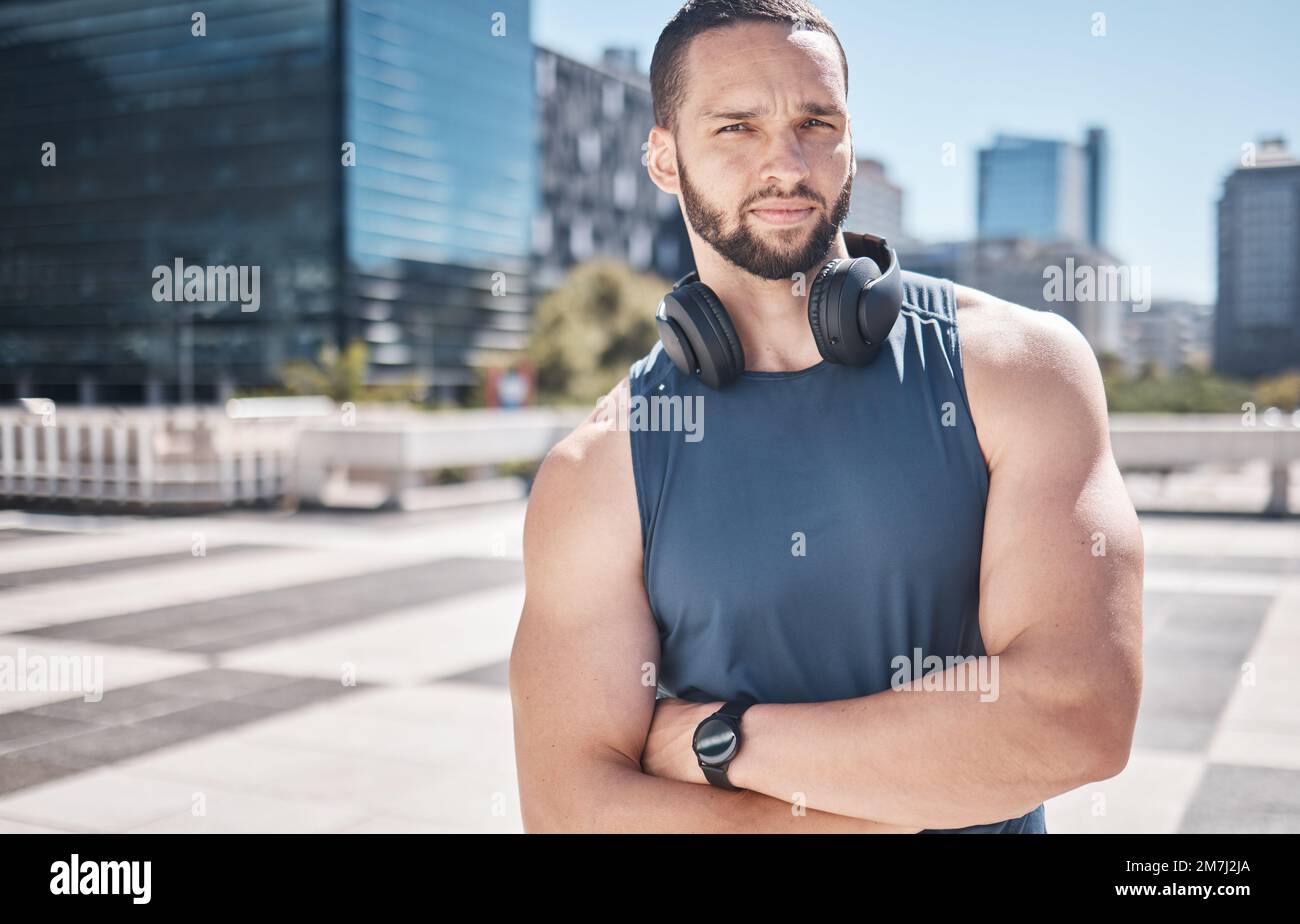 Portrait, fitness et ville avec un sportif debout bras croisés tout en écoutant de la musique pendant son entraînement. Exercice, santé et bien-être avec un Banque D'Images