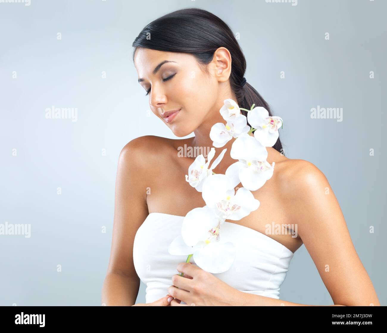 Elle a été bénie de beauté pour rivaliser mère nature. Court studio photo d'une femme attrayante tenant une fleur contre son corps. Banque D'Images