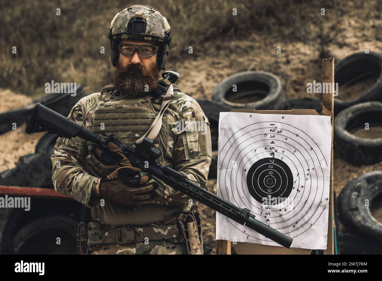Soldat mûr debout près de la cible de tir avec le fusil dans les mains Banque D'Images
