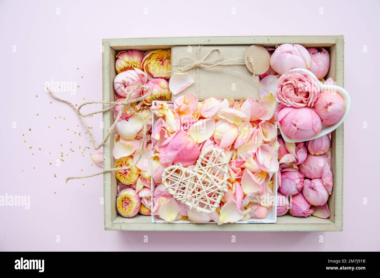 Boîte-cadeau, boutons roses et pétales. Fleurs fraîches, cadeau artisanal, coeur enchevêtré en paille. Roses dans une boîte roses roses, roses jaunes. Mode. Minimalisme. Valen Banque D'Images