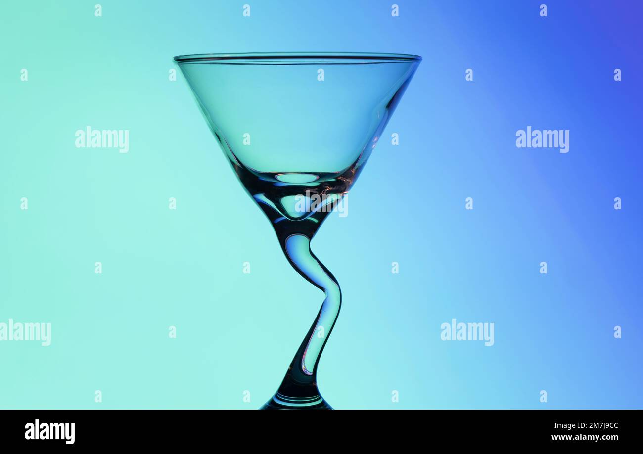 Magnifique verre à cocktail conique avec une tige en forme de bendy inhabituelle, photographié sur fond coloré produisant un motif de diffraction Banque D'Images