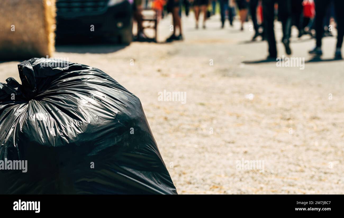 Terrue et pollution en ville, sac à ordures noir dans la rue avec les piétons qui marchent, attention sélective Banque D'Images