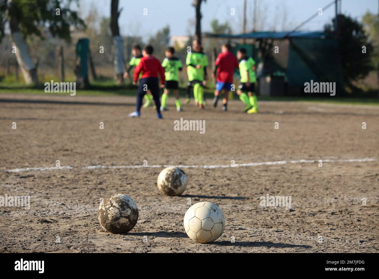 coup de pied d'une balle sur un terrain d'argile avec des garçons jouant en arrière-plan Banque D'Images