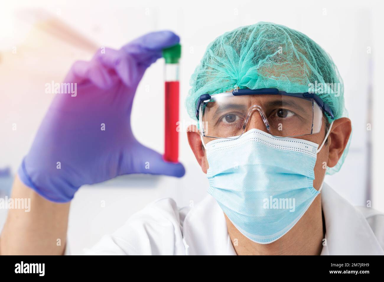 Jeune femme portant un masque facial de protection et des lunettes examinant le tube à essai en laboratoire avec un accent sur les yeux Banque D'Images