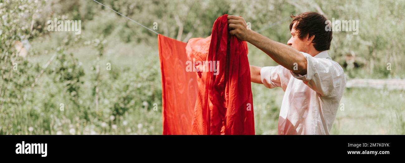 jeune corbeau mûr et candié, il fait ses devoirs et pendre la buanderie pour sécher sur une corde à linge dans la rue dans la cour du cottage de ménage du village Banque D'Images