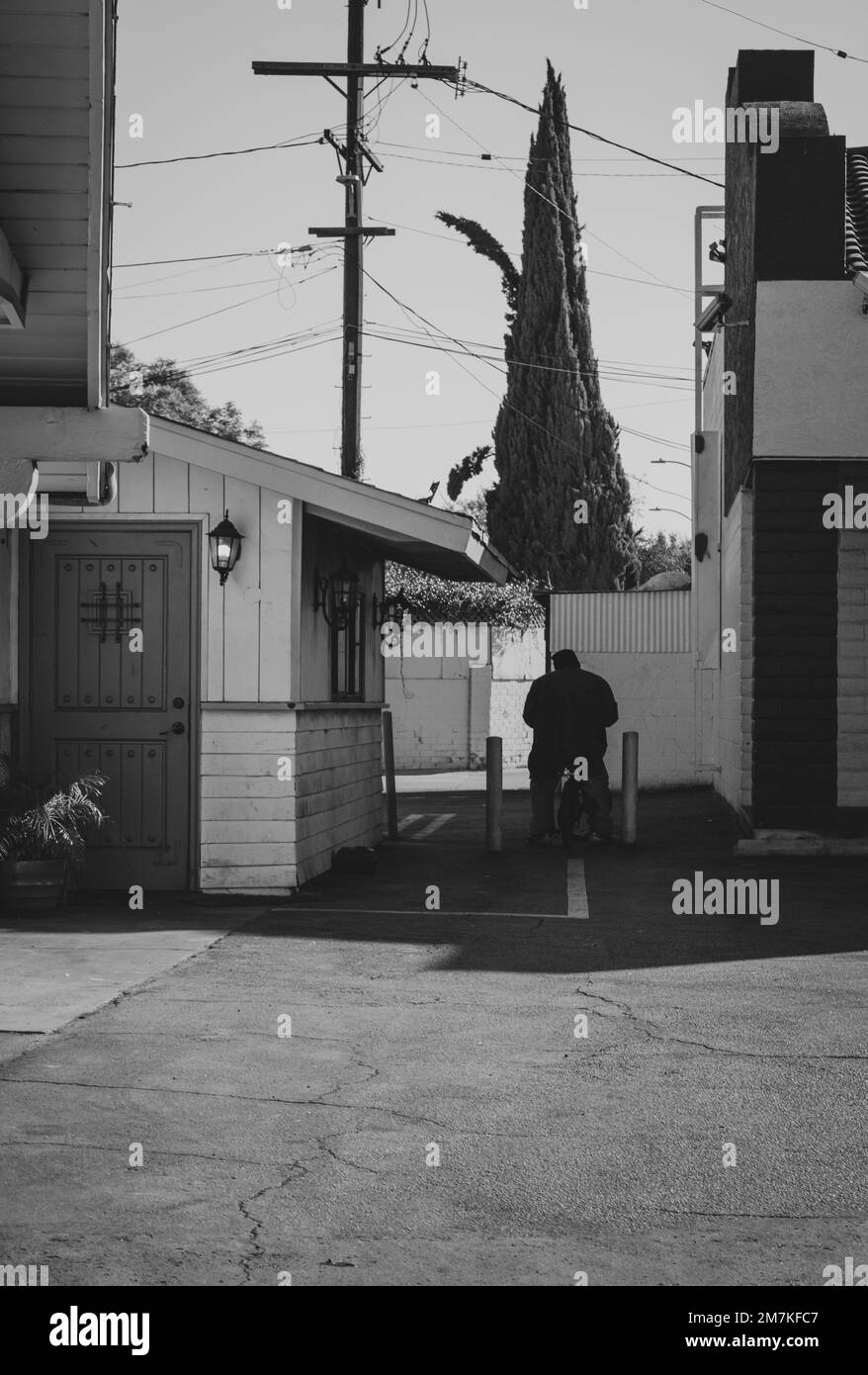 Un homme sur un vélo BMX dans une petite allée entre Metro PCS et J's Bar N Grill. Ville de Bell ca. Banque D'Images