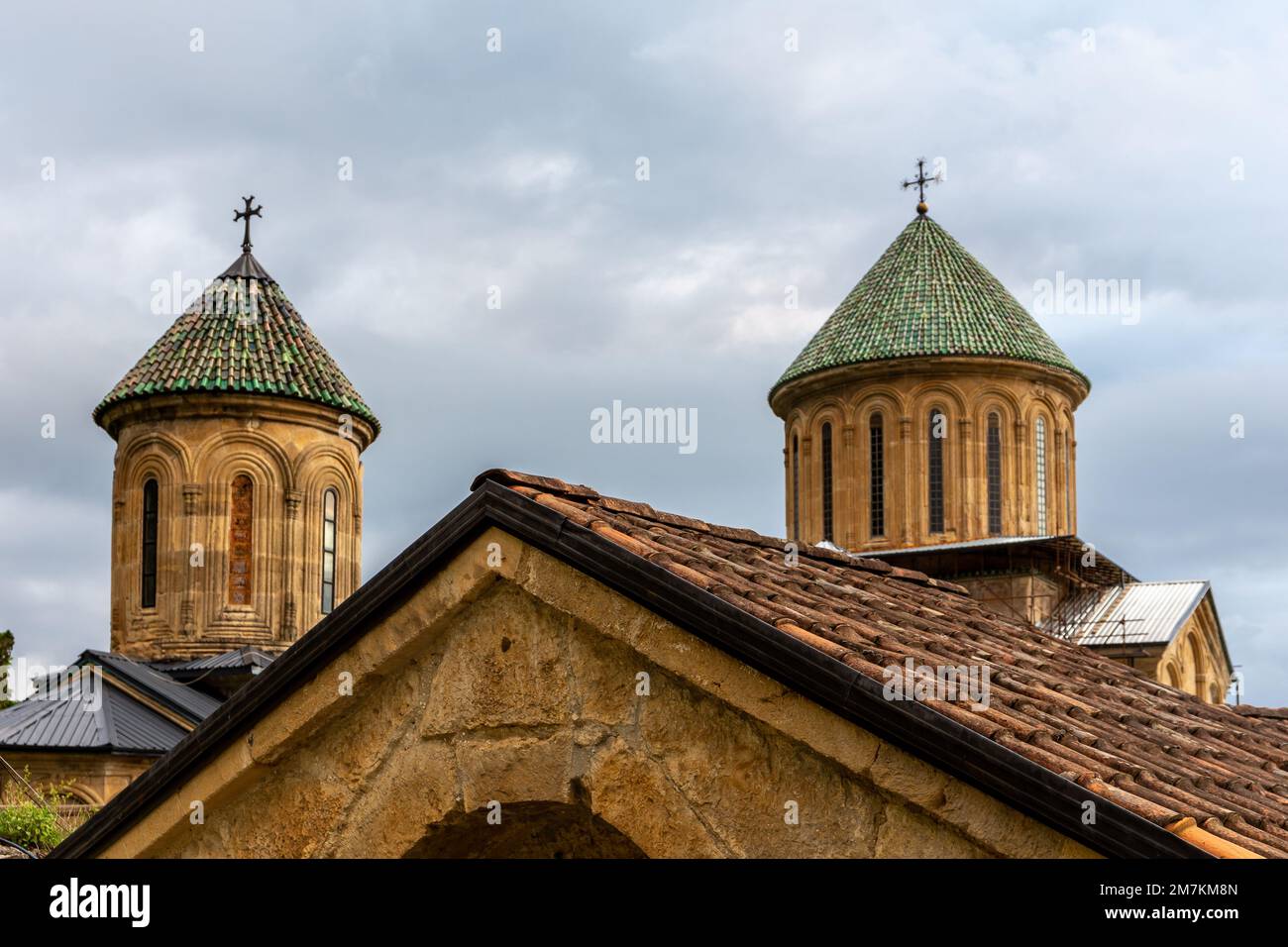 Tours du monastère des gelati, complexe monastique médiéval près de Kutaisi, Géorgie fondée par le roi David IV, église orthodoxe en pierre avec toit de tuiles vertes. Banque D'Images