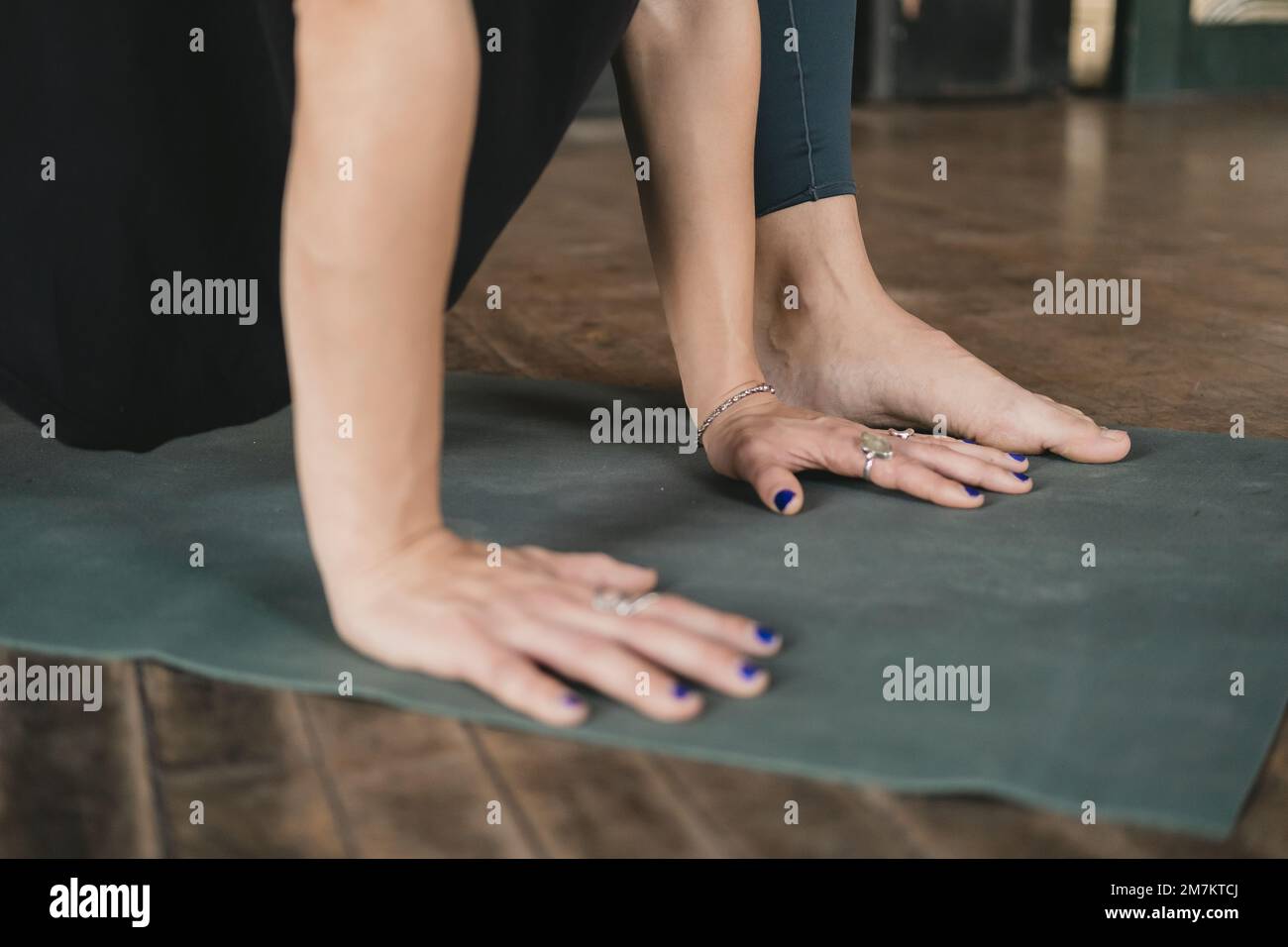 Photo en gros plan de jeunes adultes non reconnaissables yogi femelle et nouveau professeur faisant une posture de fente basse (Anjaneyasana), entraînement de yoga, pieds nus Banque D'Images