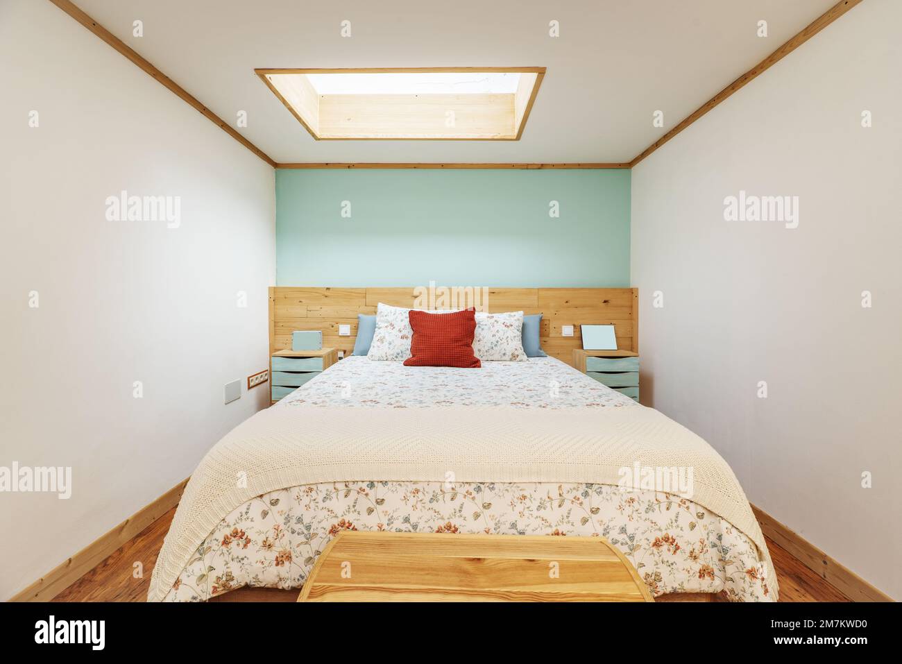Chambre avec lit double, tête de lit en pin assortie, coffre au pied, courtepointe et coussins à motifs floraux Banque D'Images