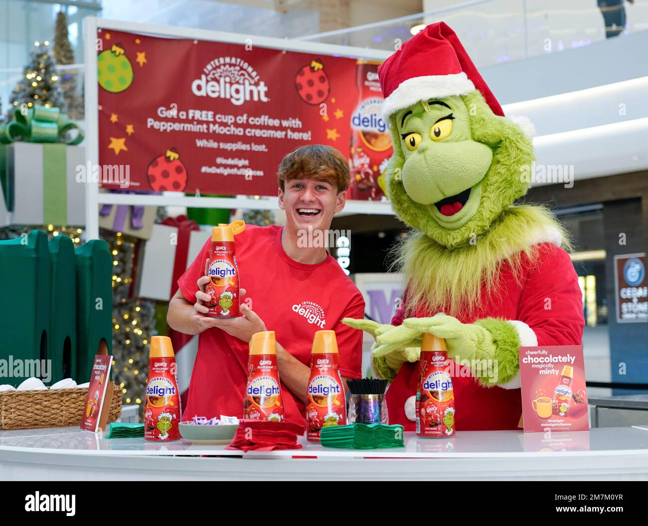 IMAGE DISTRIBUTED FOR INTERNATIONAL DELIGHT - The Grinch and TikTok star, Carter Kench, serve up coffee with International Delight Grinch Peppermint Mocha creamer at Mall of America on Thursday, Dec. 8, 2022, in Minneapolis. The beloved creamer brand offered a cheerfully chocolatey, magically minty surprise to stressed out shoppers during the busy holiday season. (Craig Lassig/AP Images for International Delight) Banque D'Images