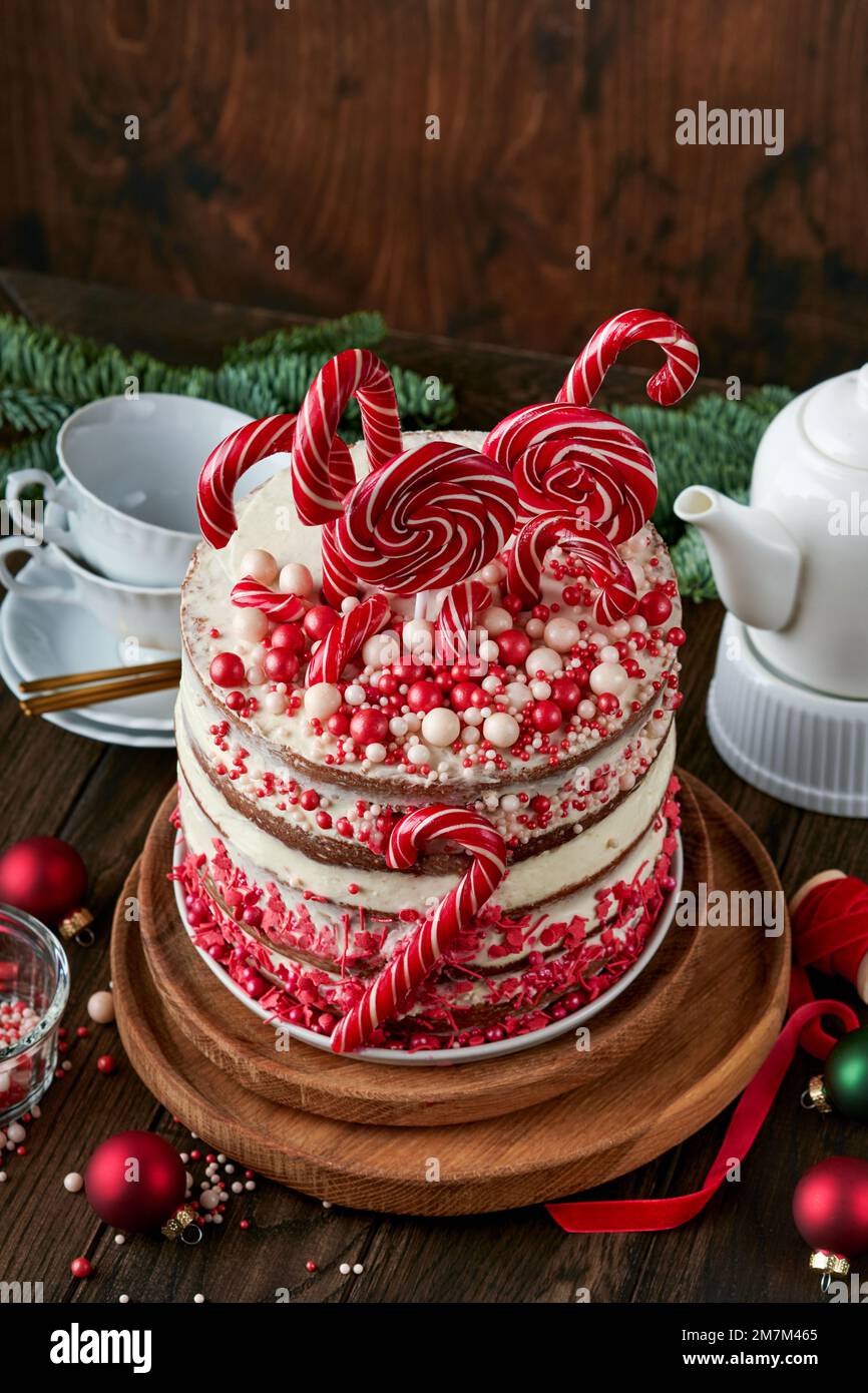 Noël plusieurs couches de gâteau décoré avec des pop lolli, confetti rouge et blanc sur le support à gâteau blanc, boules de Noël, branches de sapin sur le vieux bois rustique t Banque D'Images