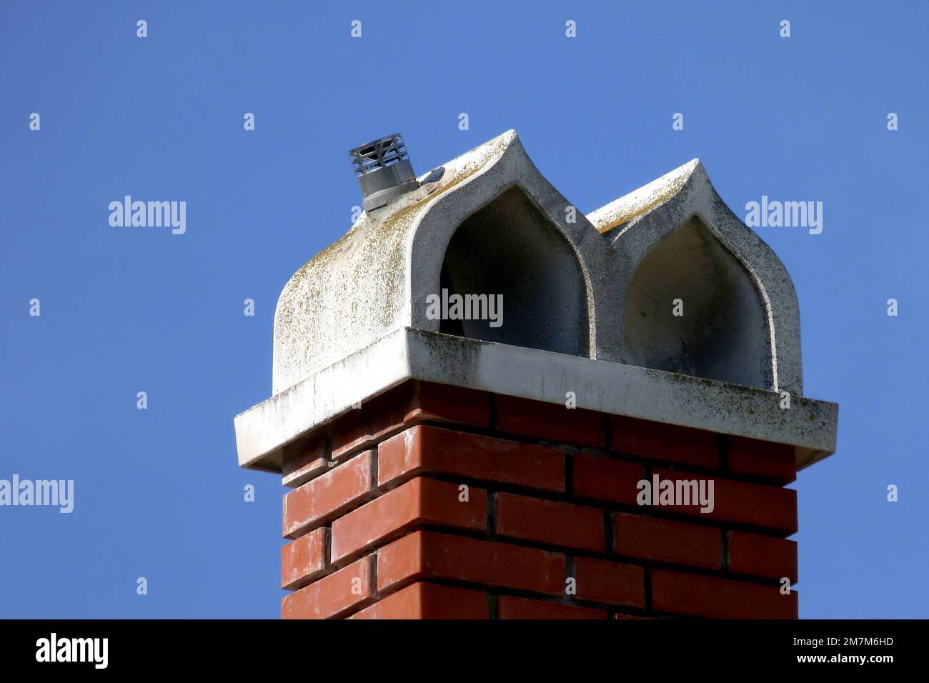 détail cheminée décorative voûtée. pierre à capuchon en béton préfabriqué blanc. dégagement de fumée en acier. pile de fumée en brique d'argile brun rouge. ciel bleu clair Banque D'Images