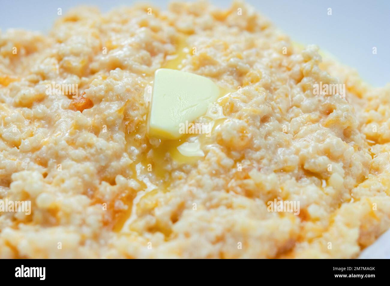 Gros plan de porridge de citrouille avec millet et beurre servi dans un bol blanc, foyer sélectif, photo horizontale. Banque D'Images