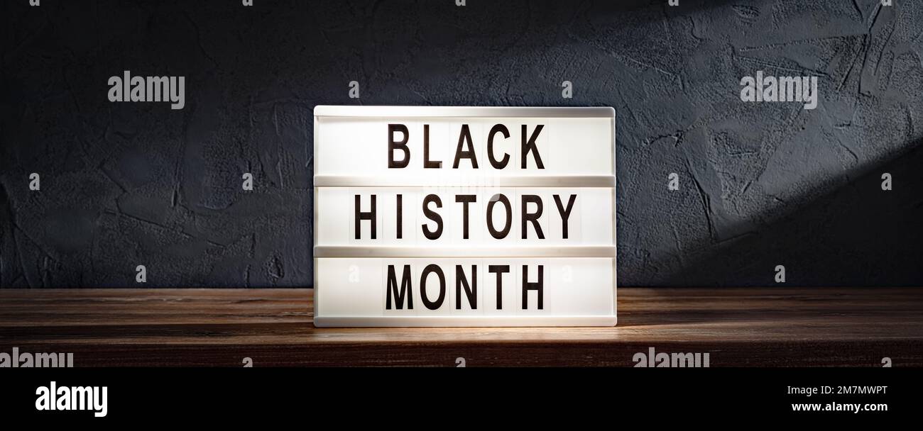 Mots du mois de l'histoire des Noirs sur la visionneuse sur une étagère en bois sur fond de mur en pierre noire Banque D'Images