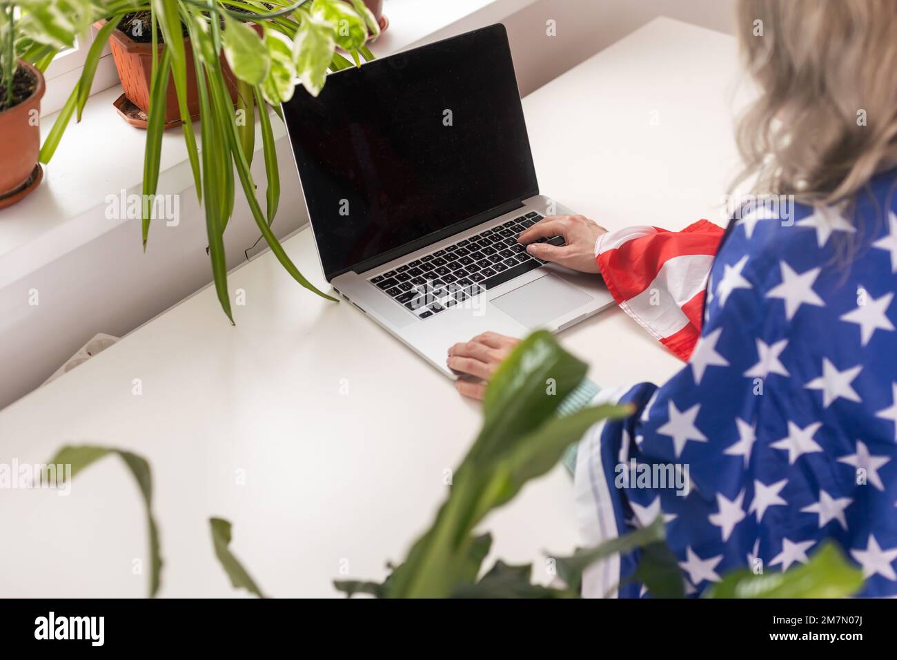 Une employée heureuse assise dans un drapeau américain, criant pour la joie sur le lieu de travail de bureau, célébrant la fête du travail ou le jour de l'indépendance des États-Unis. Banque D'Images
