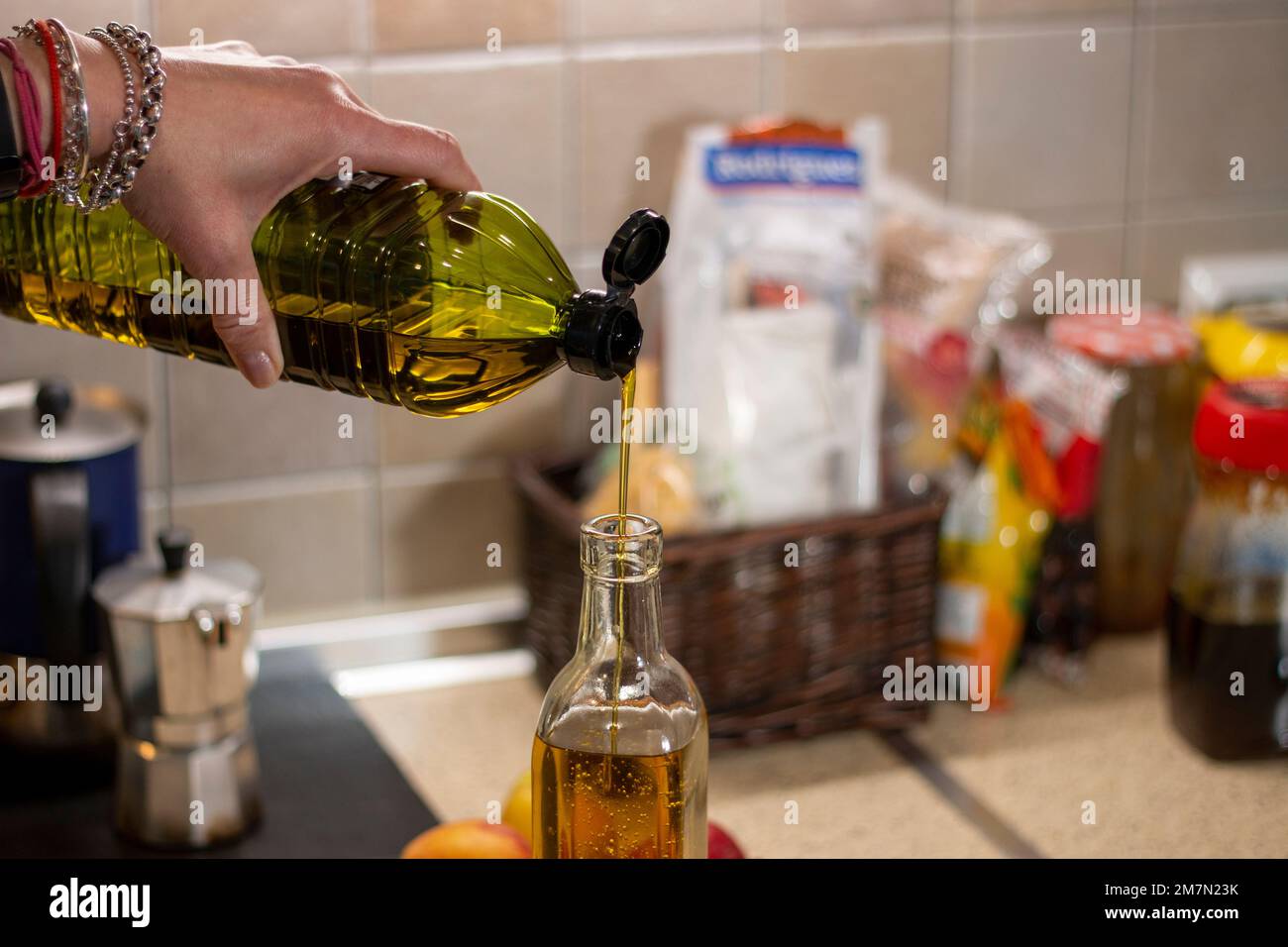 Un jet d'huile d'olive extra vierge étincelante, AOVE, comme il coule du récipient en plastique dans une bouteille en verre. Huile des oliveraies d'Espagne Banque D'Images