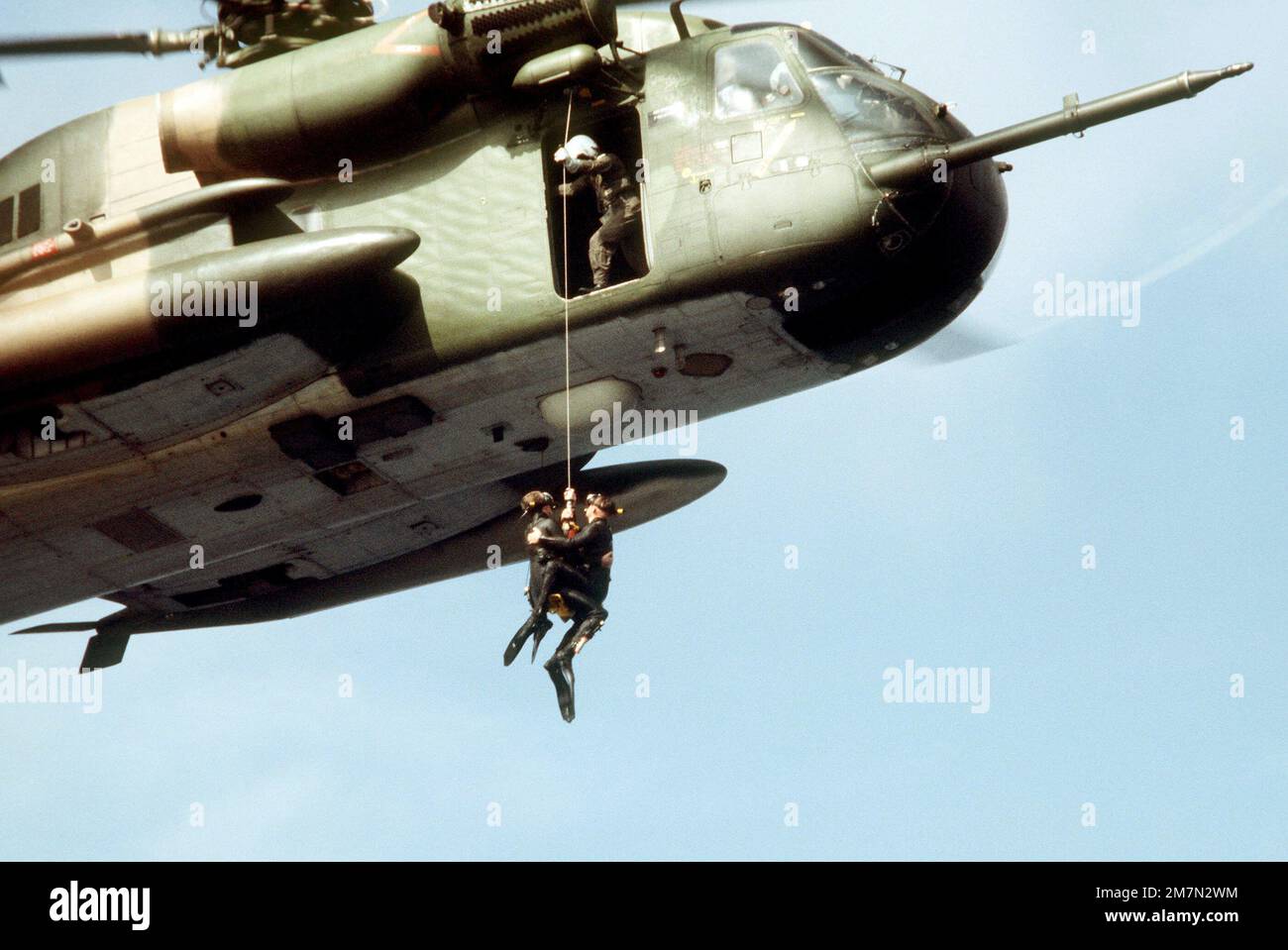 Les parasauveteurs de l'escadron de sauvetage et de récupération aérospatial 55th, Eglin AFB (Floride), sont hissés à bord d'un hélicoptère HH-53 en vol stationnaire après avoir récupéré un 'survivor' de l'eau. L'exercice de sauvetage en mer est en cours de préparation pour une production cinématographique. Pays: Golfe du Mexique Banque D'Images