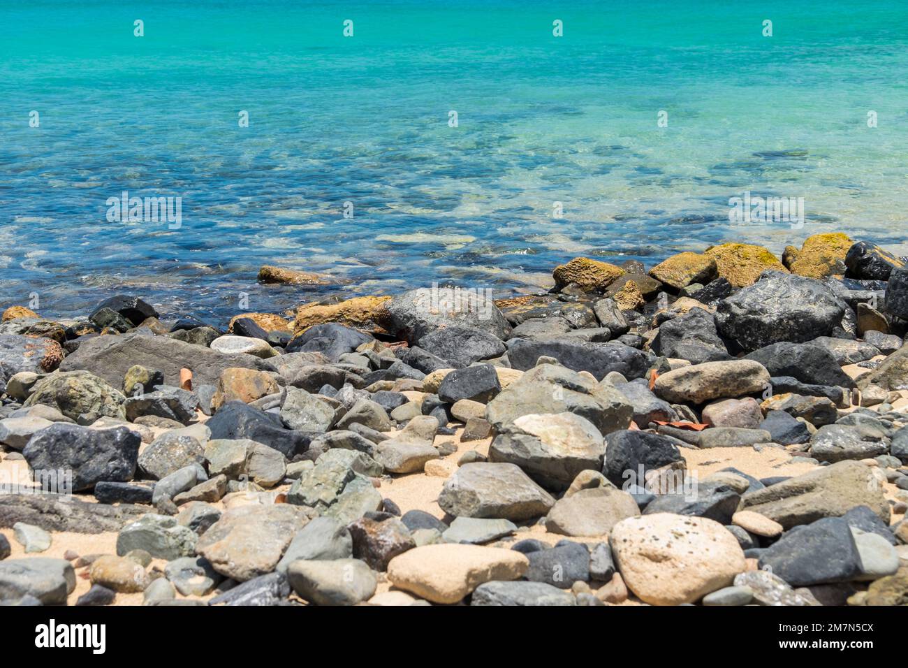 Rocky Beach et une mer turquoise calme sur une plage à Sint Marteen Banque D'Images