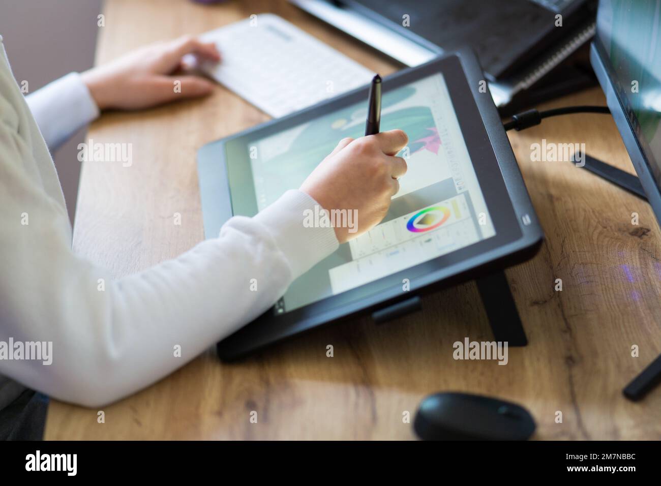 Jeune femme qui dessine sur une tablette numérique. Fille travaillant à la maison comme graphiste. Gros plan des bras d'une fille dessinant sur une tablette numérique. Banque D'Images