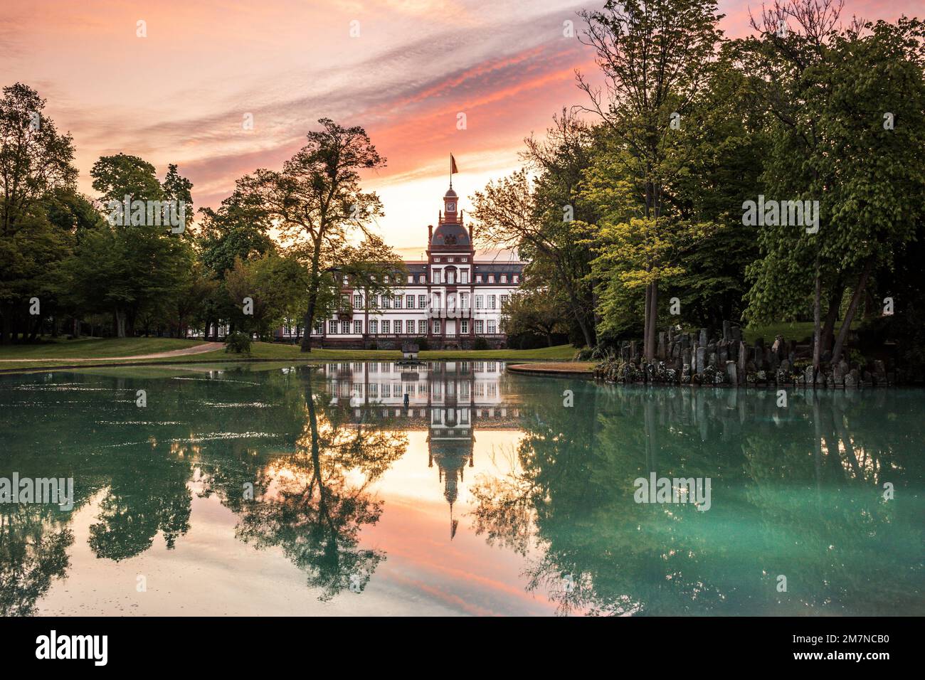 Château de Philippsruhe à Hanau en Allemagne, magnifique château sur la rivière main, grands nuages et arbres à la perfection au coucher du soleil ou au lever du soleil Banque D'Images