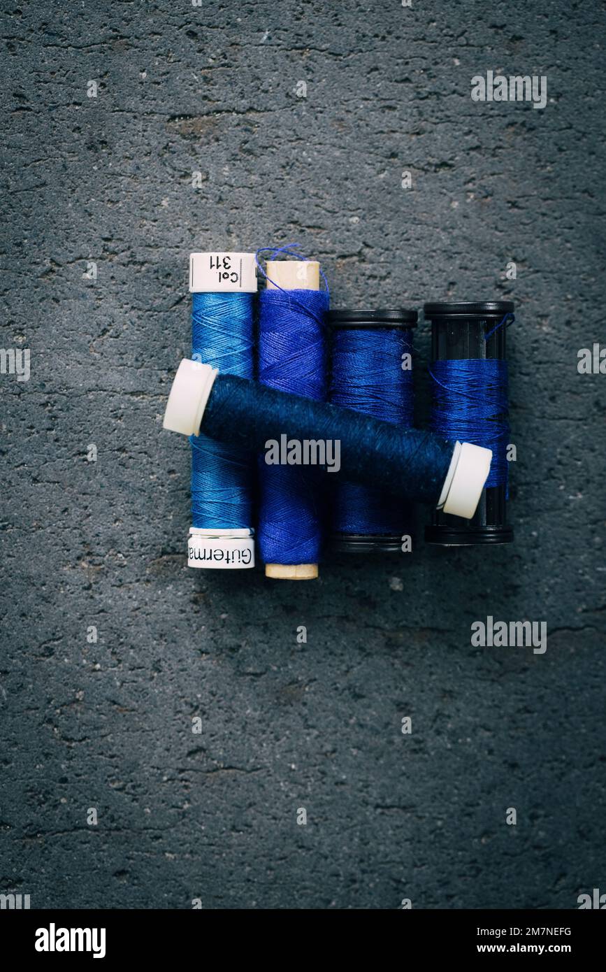 Cinq bobines de fil à coudre bleu sur sol en pierre grise Banque D'Images