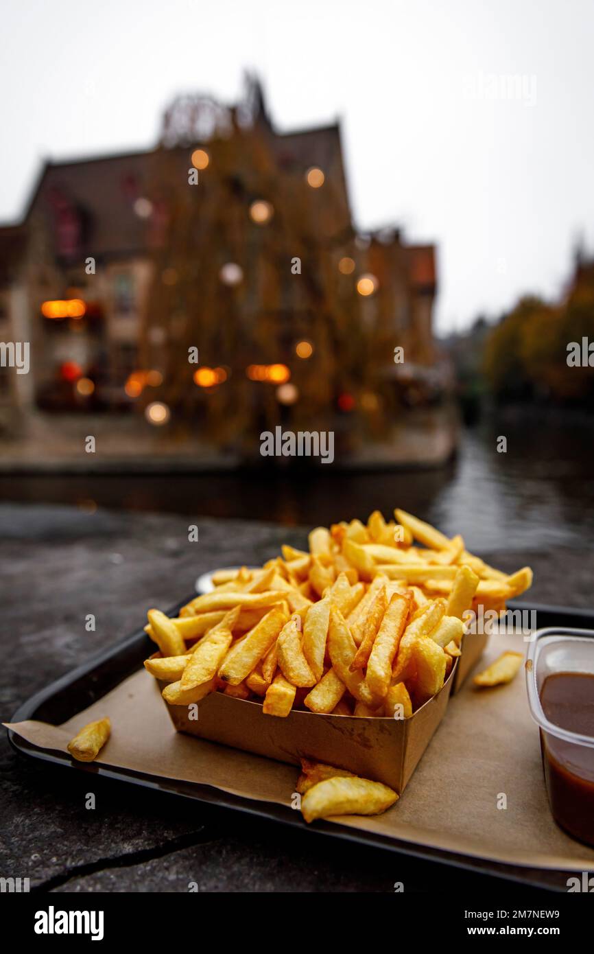 Manger de la cuisine traditionnelle de rue - les frites belges en plein air dans la vieille ville d'Europe Banque D'Images