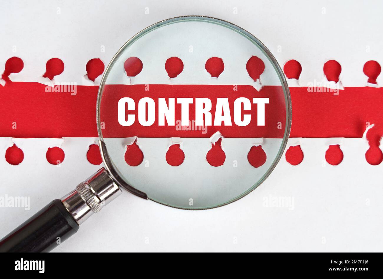 Entre deux feuilles d'un carnet sur une bande rouge avec l'inscription - Contract, il y a une loupe. Banque D'Images