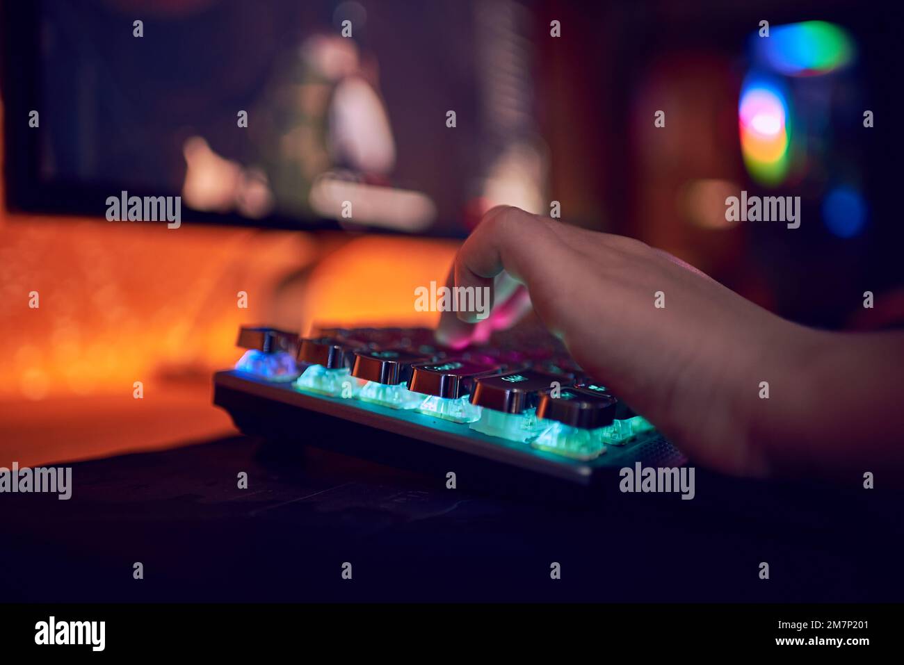 Gros plan des mains montrant un joueur en appuyant sur les boutons du clavier tout en jouant à un jeu vidéo en ligne. Voyants du clavier. La chambre est sombre. Banque D'Images