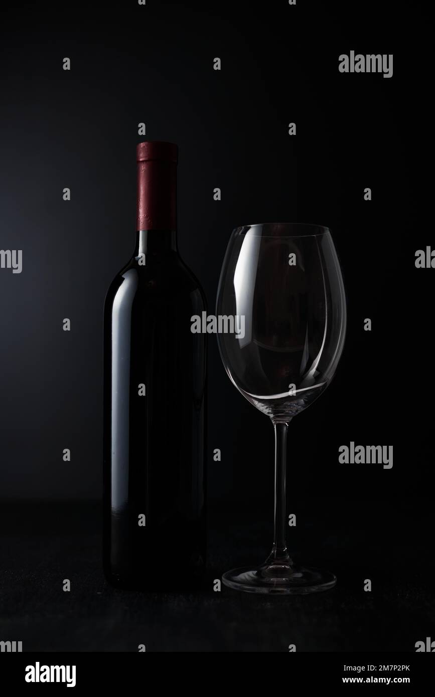 Vider le verre à vin et la bouteille sur fond sombre. Banque D'Images