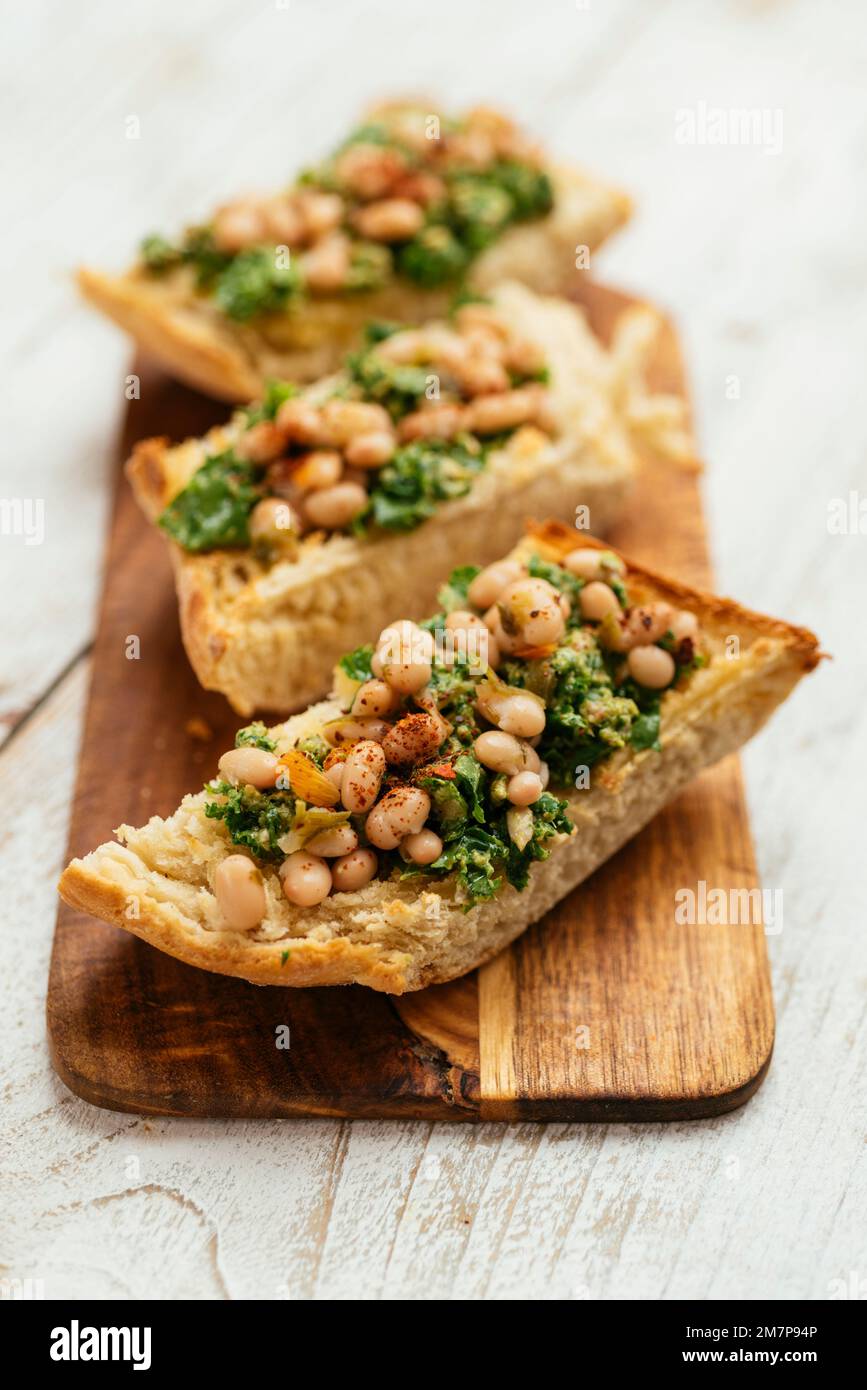 Pesto de kale vegan maison avec bruschetta de haricots blancs sur une planche à découper. Banque D'Images