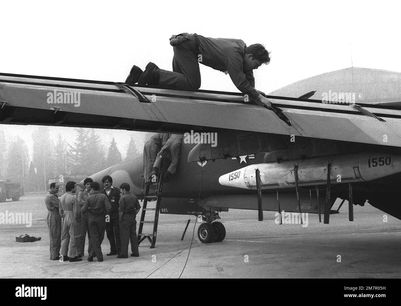 Un chef d'équipage inspecte les béquilles d'aile d'un avion F-111F tandis que les pilotes de l'armée de l'air italienne voient les commandes de vol de l'avion. L'aviateur est affecté au 48th Escadron de maintenance. Base: Aviano Air base État: Pordenone pays: Italie (ITA) Banque D'Images