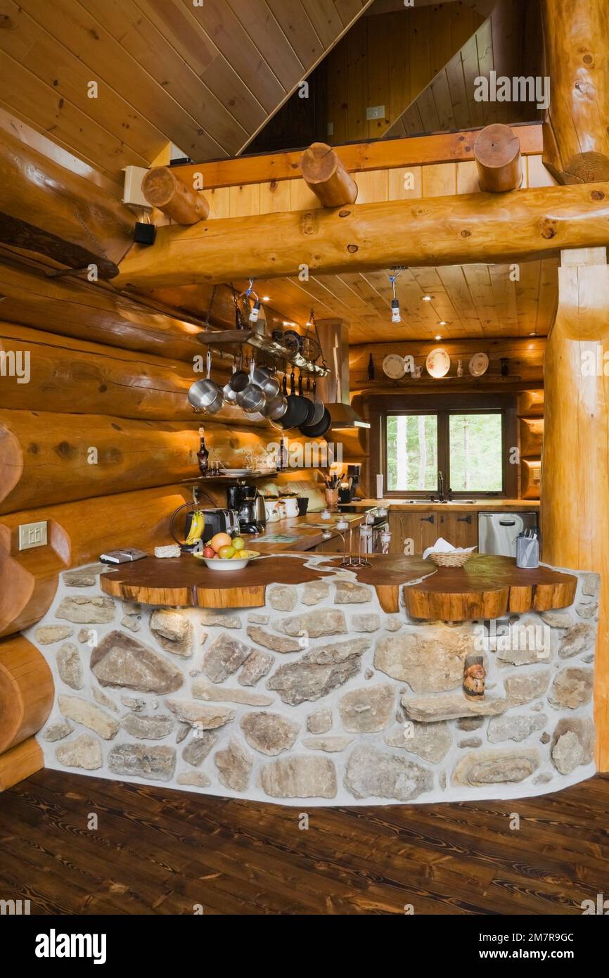 Cuisine avec barre incurvée construite avec des pierres de champ et des roches poreuses à l'intérieur de la maison scandinave en bois de cèdre rouge artisanal. Banque D'Images