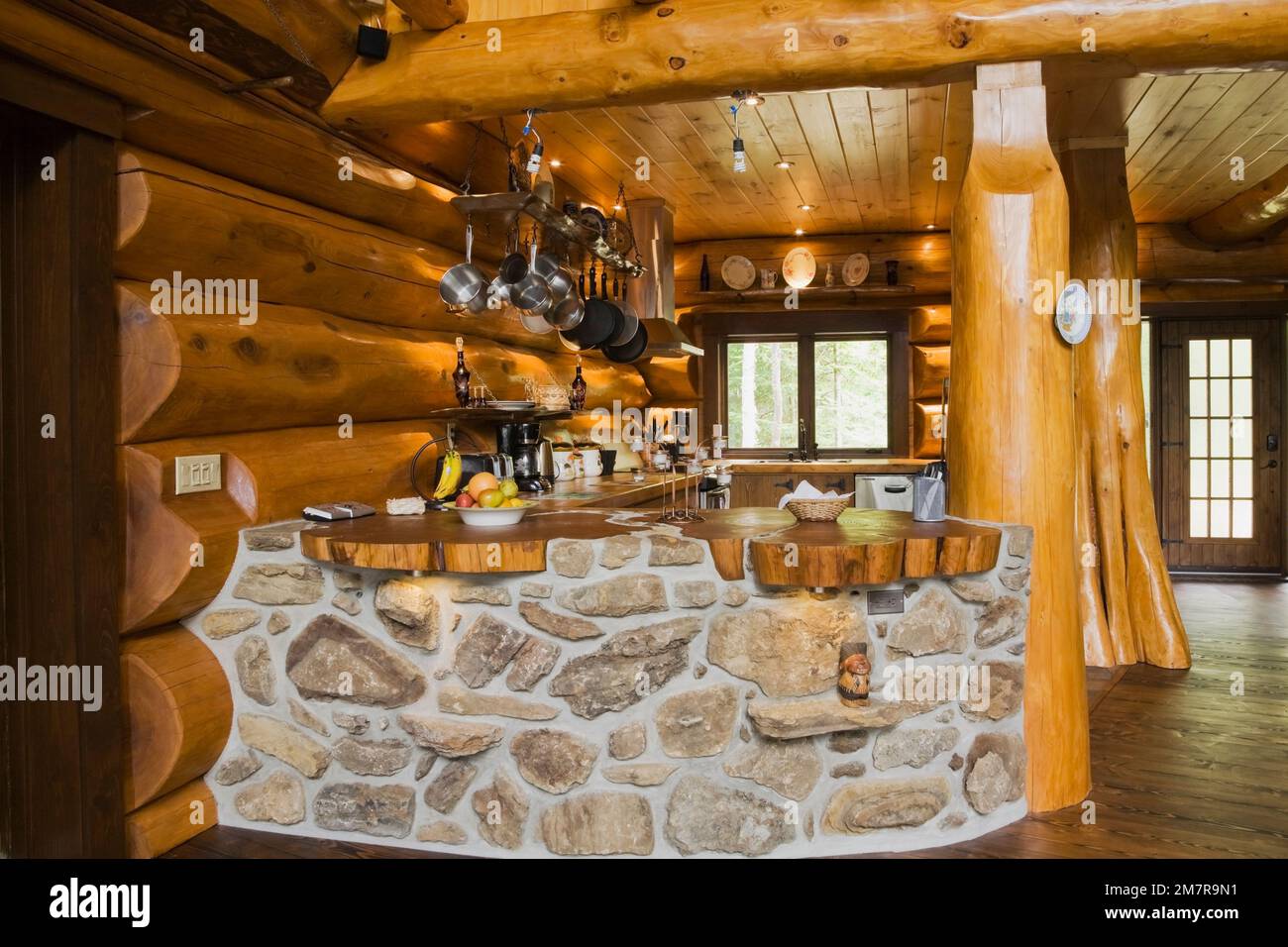 Cuisine avec barre incurvée construite avec des pierres de champ et des roches poreuses à l'intérieur de la maison scandinave en bois de cèdre rouge artisanal. Banque D'Images