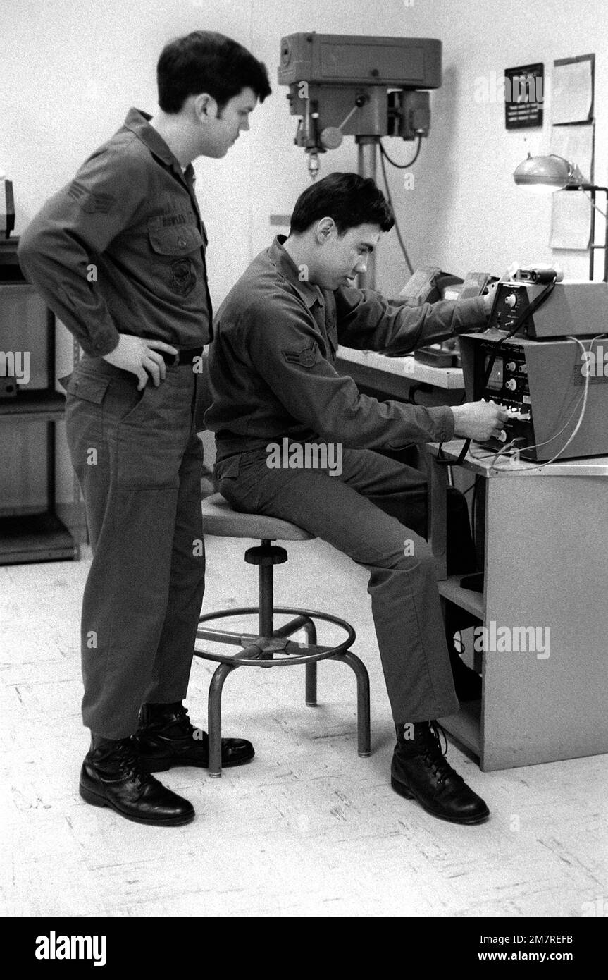 LE SGT Joseph Bowles regarde par-dessus l'épaule du A1c Dennis Dominiquez, car il utilise un testeur de synchronisation pour vérifier les vitesses d'obturation d'une caméra Leica. Les deux hommes portent des fatigues, leur uniforme de travail, et sont membres de l'escadron audiovisuel 1361st. Base: Arlington État: Virginia (va) pays: Etats-Unis d'Amérique (USA) Banque D'Images