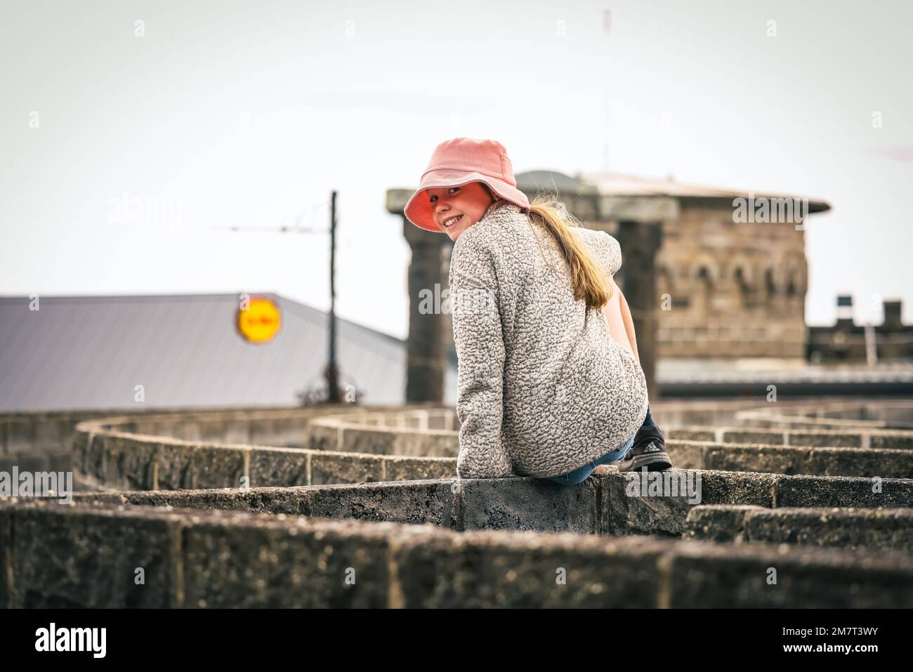 Fille assise sur le mur de Maze au château de Kryal, Ballarat Victoria Australie Banque D'Images