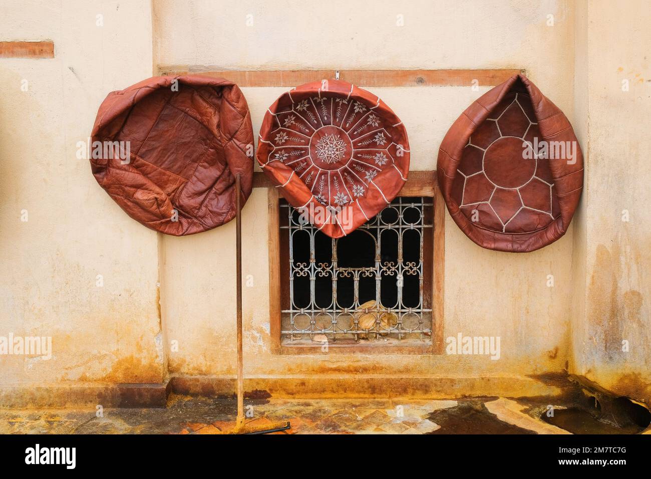 Fès, Maroc - trois poufs en cuir rond, marron, traité et non farci sont accrochés au mur pour sécher à la Tannery de Chouara à Fès el Bali. Marchandises destinées à la vente ou à l'exportation. Banque D'Images