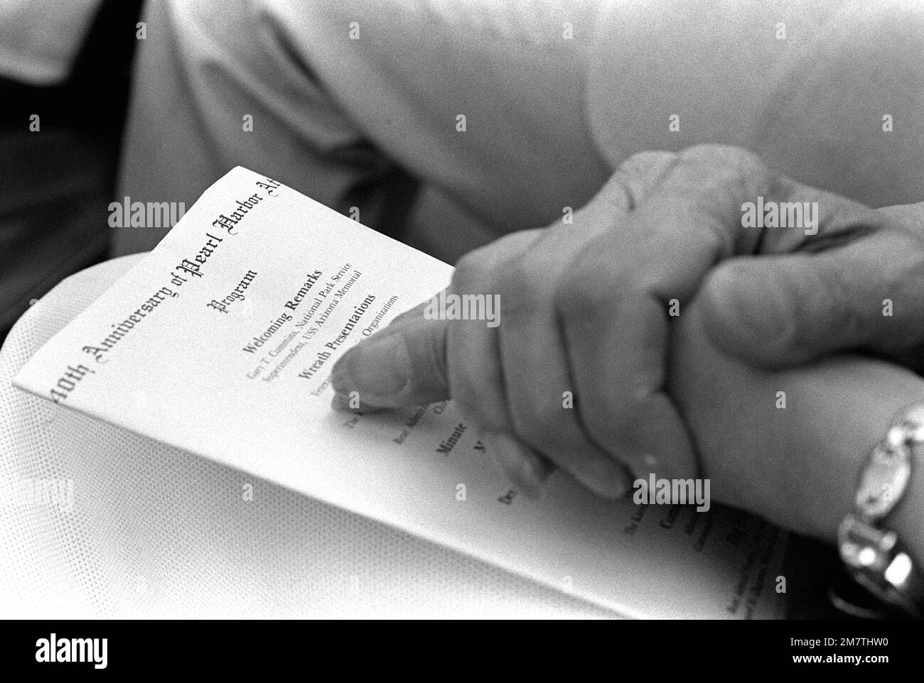 Les mains pliées d'un invité reposent sur le programme de la cérémonie à bord du USS ARIZONA Memorial commémorant le 40th anniversaire de l'attaque japonaise sur Pearl Harbor. Base: Pearl Harbor État: Hawaï (HI) pays: Etats-Unis d'Amérique (USA) Banque D'Images