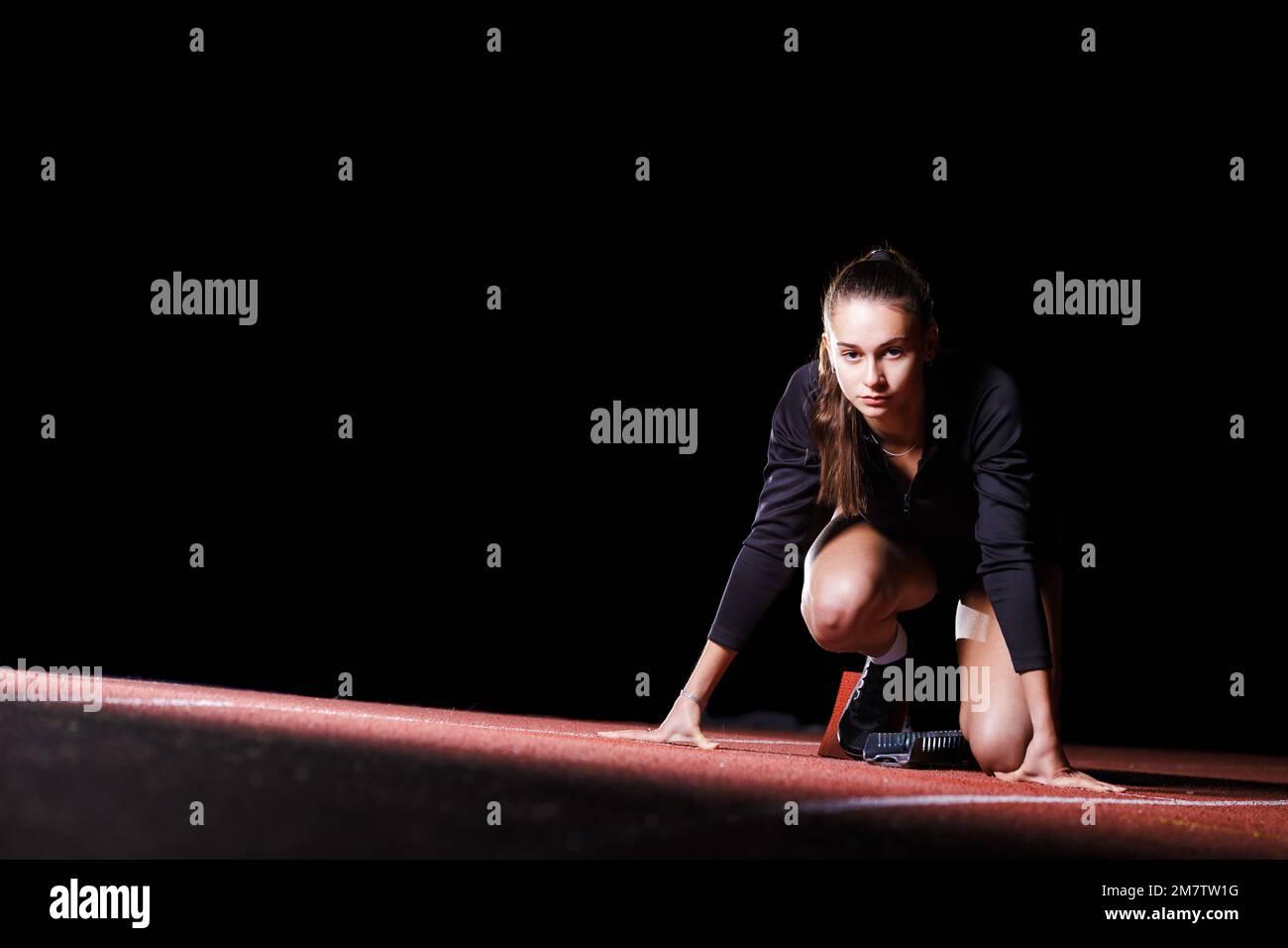 Jeune sportswoman aux blocs de départ avant de courir sprint Banque D'Images