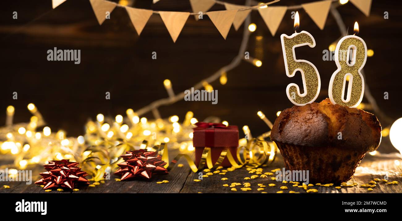 Numéro 58 bougies dorées festives dans un gâteau, arrière-plan de vacances en bois. cinquante-huit ans depuis la naissance. le concept de célébrer une naissance Banque D'Images