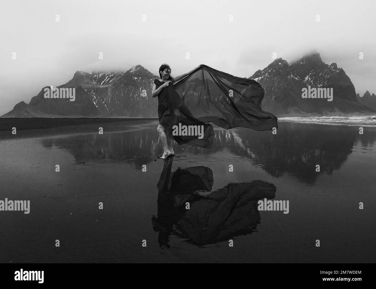 Élégante dame enveloppée de mousseline sur la plage photographie monochrome pittoresque Banque D'Images