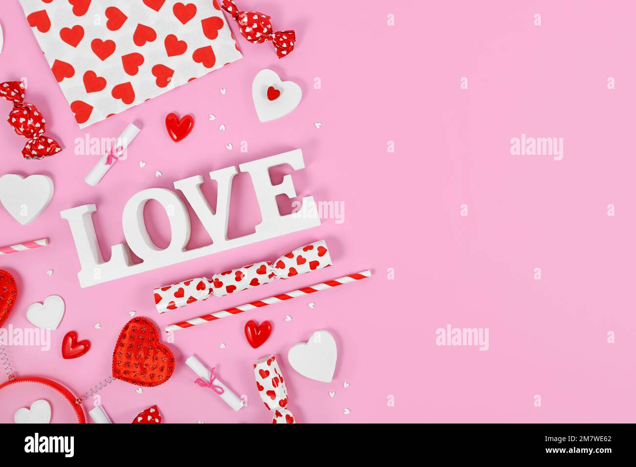 Décoration de la Saint-Valentin avec texte d'amour, ornements en coeur et arrosez sur fond rose avec espace de copie Banque D'Images