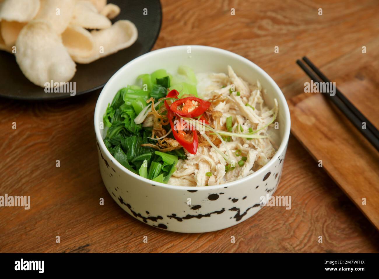 Porridge de riz indonésien avec viande de poulet déchiquetée, servi avec quelques légumes et condiments Banque D'Images
