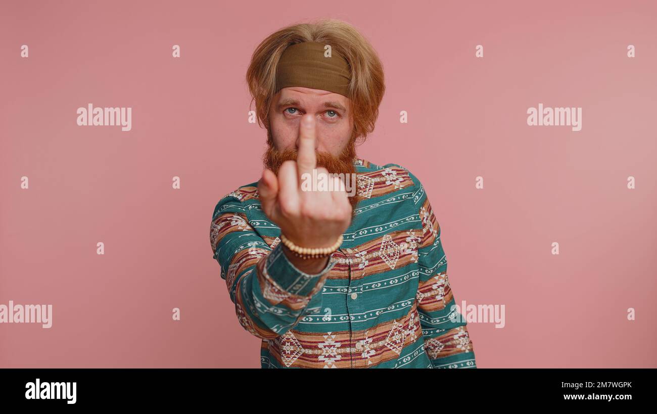 Agressif, fou de hooligan hippie, homme à tête rouge dans une chemise en forme de motif, montrant autour de ses doigts moyens, manifestant une protestation avec un geste impoli de mépris, rejetant la communication. Petit garçon Banque D'Images
