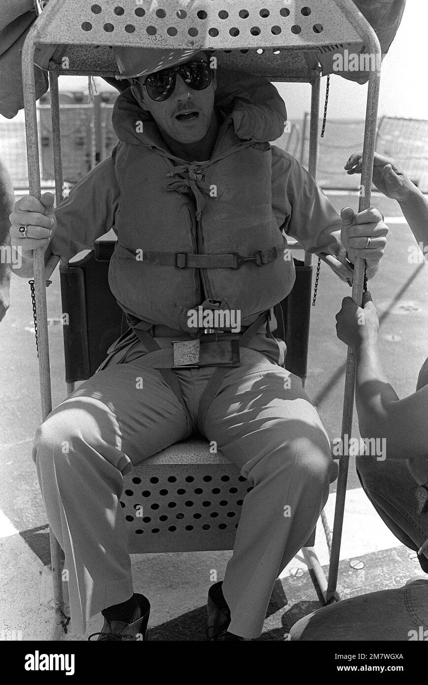 Aumônier (LT.) Gary Hill attend dans la chaise du bateau pour le transfert de la frégate USS WHIPPLE (FF-1062) à la frégate USS RATHBURNE (FF-1057). Le transfert en mer sera effectué à l'aide d'une ligne haute de manille. Pays : inconnu Banque D'Images