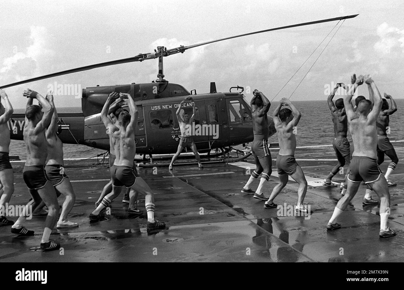 Les membres du 2nd Bataillon, 3rd Marine Landing Team, participent à des exercices physiques pendant leur séjour à bord du navire d'assaut amphibie USS NEW ORLEANS (LPH-11). Un hélicoptère UH-1N Iroquois est stationné sur le pont de vol à côté des Marines. Pays: Océan Indien (CIO) Banque D'Images