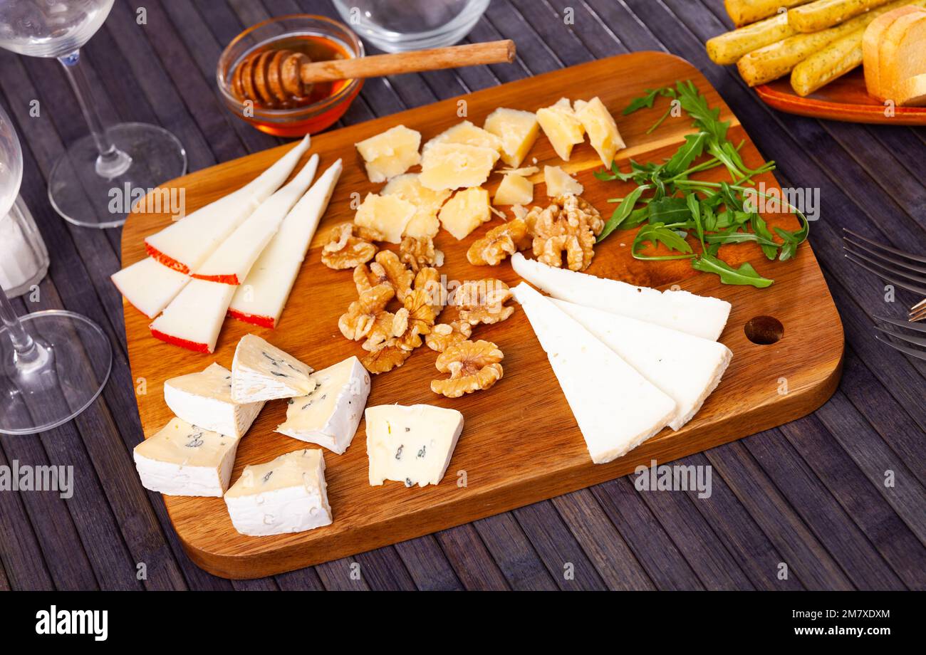 Différents types de fromage servis sur bois avec du miel, des tranches de noix Banque D'Images