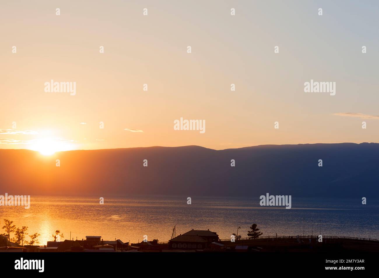 Coucher de soleil sur le lac Baikal sur les montagnes à l'horizon. Les derniers rayons du soleil se reflètent dans l'eau pour laisser entrer l'obscurité de la nuit. Banque D'Images