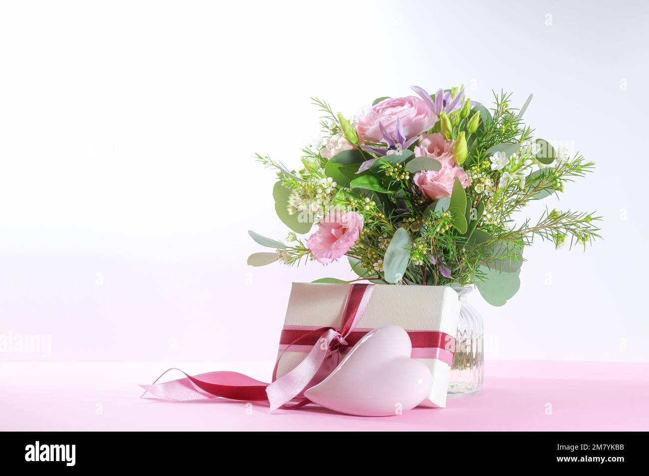 Fleurs, cadeau et coeur rose clair, symbole romantique d'amour pour des vacances comme mariage, jour de la Saint-Valentin, anniversaire ou jour de la mère, fond lumineux avec Banque D'Images